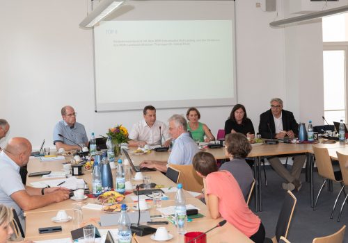 Viele Menschen sitzen in einem Raum und diskutieren.