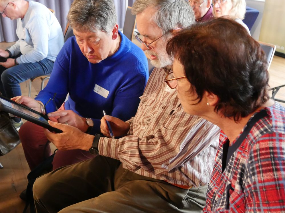 Drei Seniorinnen und Senioren schauen gemeinsam in ein Tablet